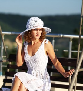 Молодая красивая девушка в белом платье и белой шляпке на море